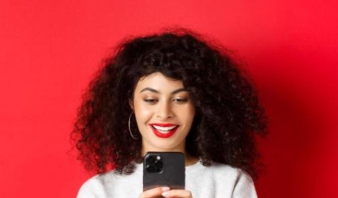 Mujer de cabello crespo sostiene su celular