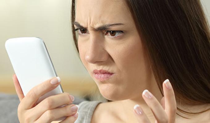 Mujer mirando el celular: mensajes falsos de WhatAspp