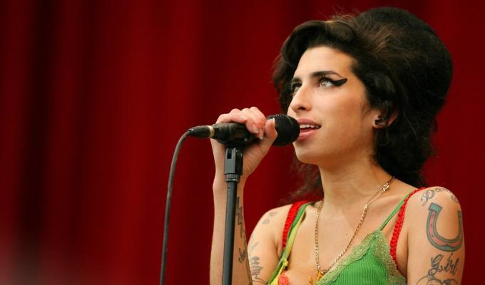 Amy Winehouse mirando hacia arriba mientras canta