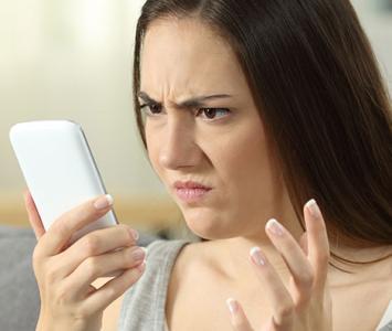 Mujer mirando el celular: mensajes falsos de WhatAspp